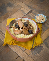 Tagine with couscous, almonds and prunes on a yellow cloth
