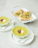 Two small soup bowls with courgetty curry soup and Indian bread