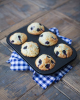 Muffin tin with six blueberry pastries on a wooden background