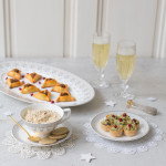 Three plates of festive fingerfood with champagne glasses and winter decoration