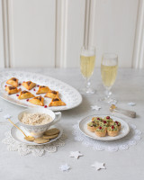 Three plates of festive fingerfood with champagne glasses and winter decoration